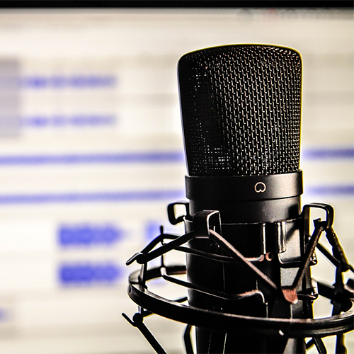 A studio microphone in front of an audio editing screen